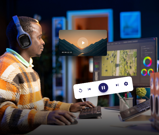 Editor at a monitor with video playback controls and color grading UI
